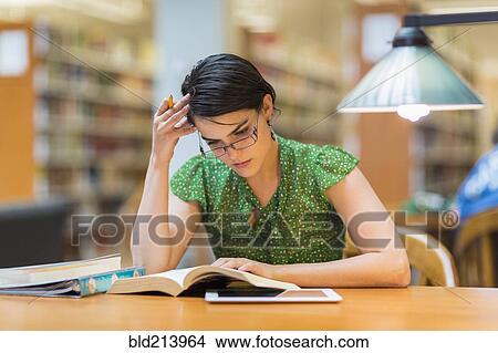 Picture - Mixed race student studying in library. Fotosearch