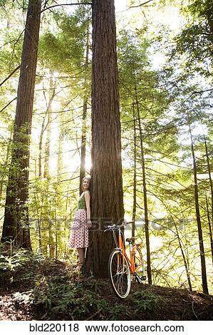 Stock Photo - Mixed race woman and bicycle in forest. Fotosearch