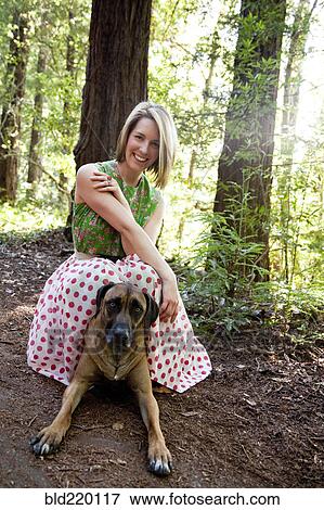 Stock Photo - Mixed race woman and dog in forest. Fotosearch