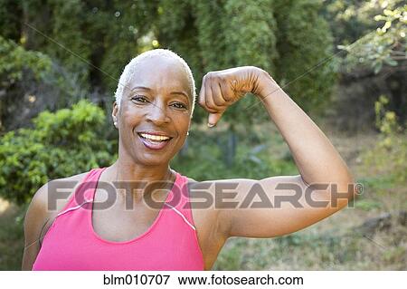 Mixed race woman flexing muscles outdoors View Large Photo Image Stock Photo - Mixed race woman flexing muscles outdoors. Fotosearch