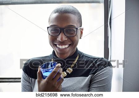Stock Photo - Mixed race woman having drink at window. Fotosearch