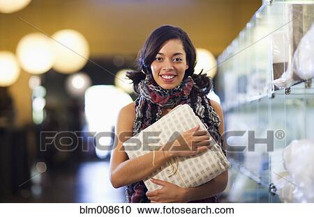 Mixed race woman holding purchase in store View Large Photo Image Stock Image - Mixed race woman holding purchase in store. Fotosearch