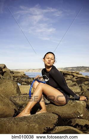 Mixed race woman holding snorkel on rocks View Large Photo Image Stock Photo - Mixed race woman holding snorkel on rocks. Fotosearch
