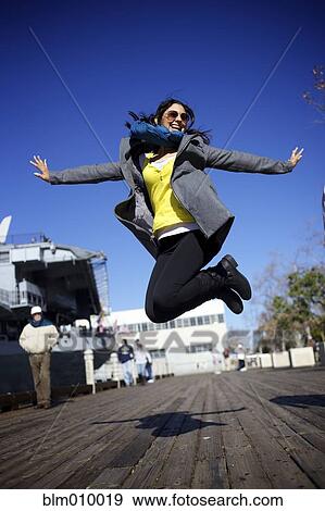 Mixed race woman jumping on boardwalk View Large Photo Image Stock Photo - Mixed race woman jumping on boardwalk. Fotosearch