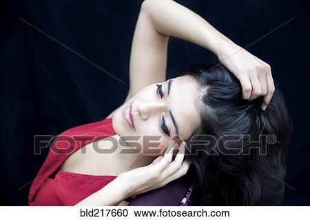 Stock Image - Mixed race woman leaning on armchair. Fotosearch
