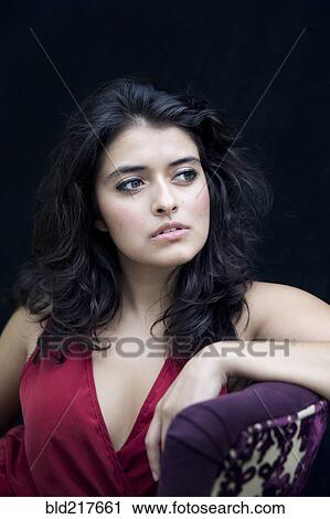Stock Image - Mixed race woman leaning on armchair. Fotosearch