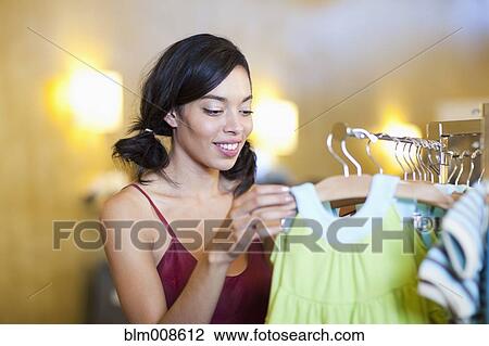 Mixed race woman looking at children's clothing in store View Large Photo Image Stock Image - Mixed race woman looking at children's clothing in store. Fotosearch