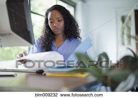 Stock Image - Mixed race woman looking at paperwork. Fotosearch