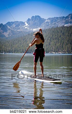 Stock Image - Mixed race woman on paddle board in Lake Tahoe, California, United States. Fotosearch