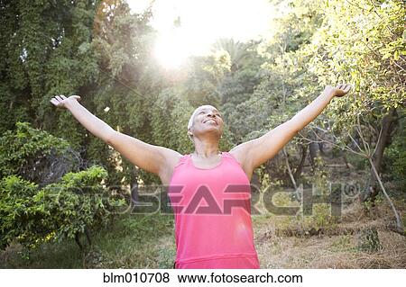 Stock Photo - Mixed race woman outdoors with arms raised. Fotosearch