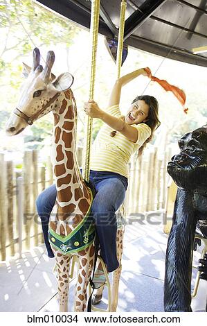 Mixed race woman riding carousel View Large Photo Image Picture - Mixed race woman riding carousel. Fotosearch