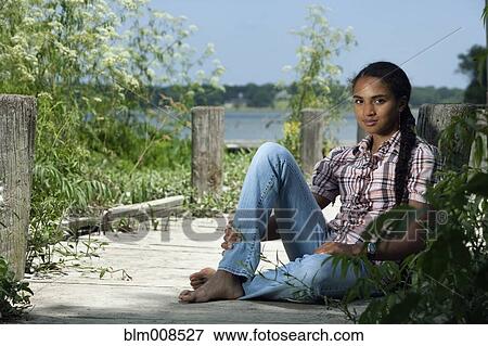 Mixed race woman sitting on dock near lake View Large Photo Image Stock Photo - Mixed race woman sitting on dock near lake. Fotosearch