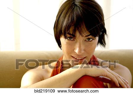Stock Photo - Mixed race woman sitting on sofa. Fotosearch