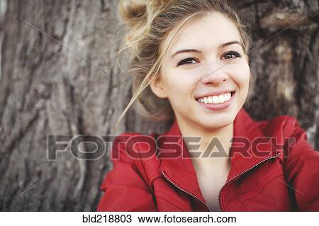 Stock Image - Mixed race woman smiling near tree. Fotosearch