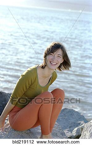 Mixed race woman smiling on rocks at beach View Large Photo Image Stock Image - Mixed race woman smiling on rocks at beach. Fotosearch