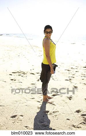 Stock Image - Mixed race woman standing on beach. Fotosearch