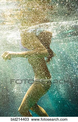 Stock Image - Mixed race woman swimming in ocean. Fotosearch