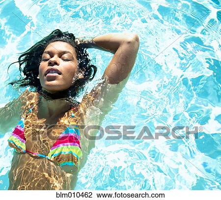 Stock Image - Mixed race woman swimming in swimming pool. Fotosearch
