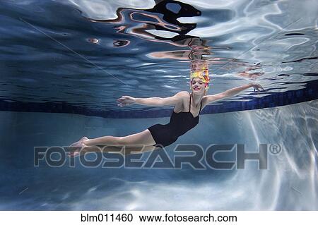 Stock Image - Mixed race woman swimming underwater. Fotosearch