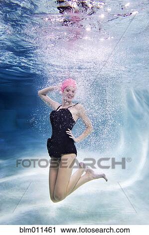 Stock Image - Mixed race woman swimming underwater. Fotosearch