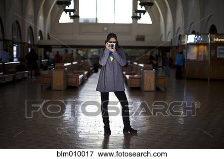 Stock Photo - Mixed race woman taking photographs in historic building. Fotosearch