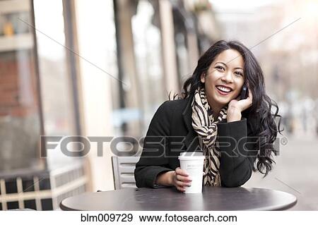 Mixed race woman talking on cell phone and drinking coffee View Large Photo Image Stock Photo - Mixed race woman talking on cell phone and drinking coffee. Fotosearch
