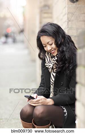 Mixed race woman text messaging on cell phone View Large Photo Image Stock Image - Mixed race woman text messaging on cell phone. Fotosearch