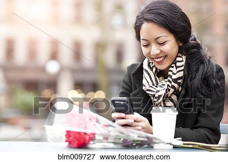 Mixed race woman text messaging on cell phone View Large Photo Image Stock Photo - Mixed race woman text messaging on cell phone. Fotosearch