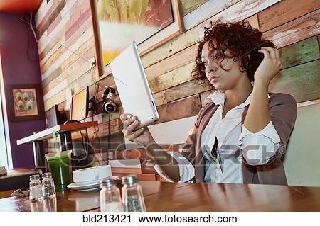Mixed race woman using tablet computer in cafe View Large Photo Image Stock Image - Mixed race woman using tablet computer in cafe. Fotosearch