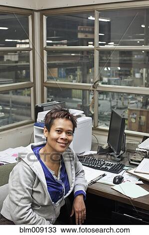 Stock Image - Mixed race woman working in factory office. Fotosearch