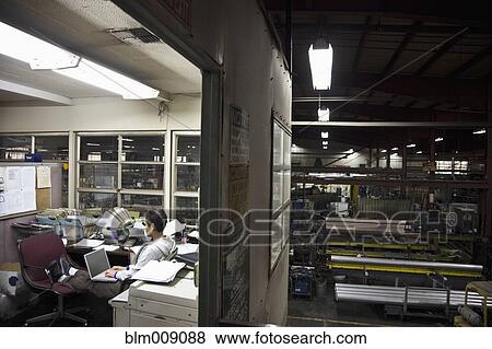 Stock Photo - Mixed race woman working in factory office. Fotosearch