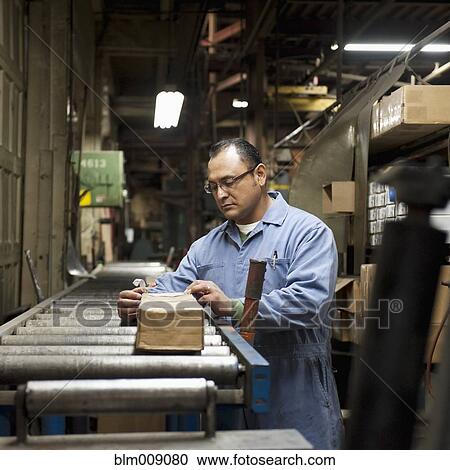 Mixed race worker looking at box in factory View Large Photo Image Stock Image - Mixed race worker looking at box in factory. Fotosearch