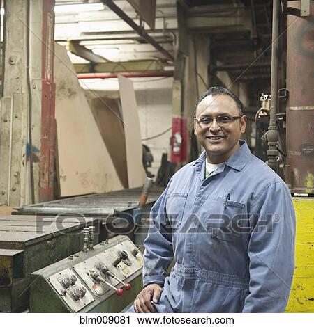 Stock Image - Mixed race worker standing in factory. Fotosearch