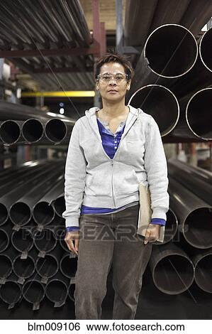 Mixed race worker standing near metal pipes in factory View Large Photo Image Stock Photograph - Mixed race worker standing near metal pipes in factory. Fotosearch