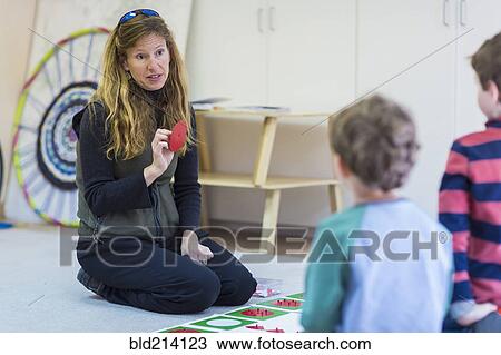 Stock Image - Montessori teacher talking to students in classroom. Fotosearch