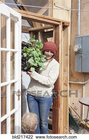Stock Image - Mother and child carrying plants in backyard. Fotosearch