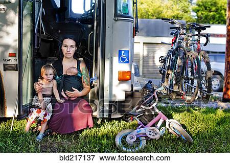 Stock Photo - Mother and children sitting in bus doorway. Fotosearch