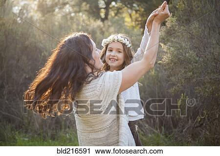 Stock Image - Mother and daughter dancing in park. Fotosearch