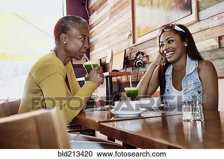 Stock Image - Mother and daughter drinking juice in cafe. Fotosearch