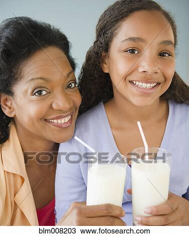 Stock Image - Mother and daughter drinking milk together. Fotosearch