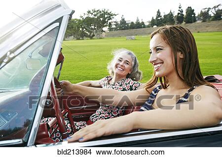 Picture - Mother and daughter driving in classic convertible. Fotosearch