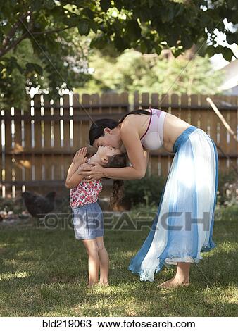 Stock Image - Mother and daughter hugging in backyard. Fotosearch
