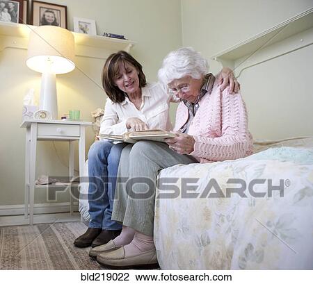 Stock Image - Mother and daughter looking at photo album. Fotosearch