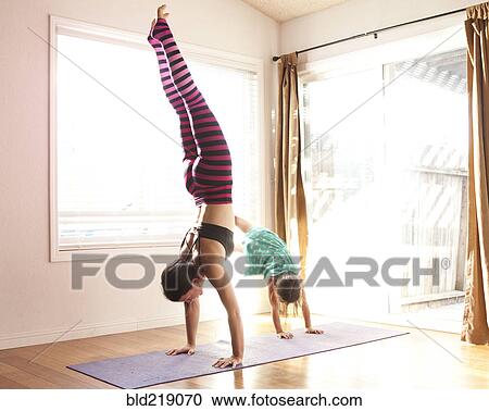 Stock Image - Mother and daughter practicing yoga in studio. Fotosearch