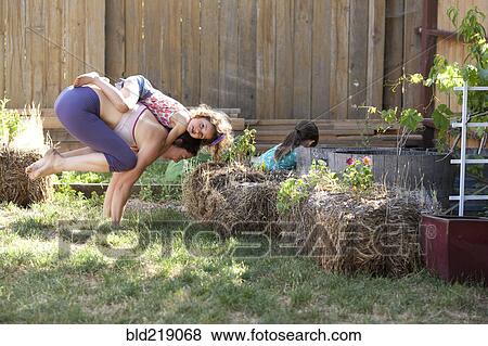Stock Photo - Mother and daughter practicing yoga in backyard. Fotosearch