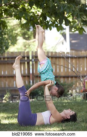 Stock Photography - Mother and daughter practicing yoga in backyard. Fotosearch