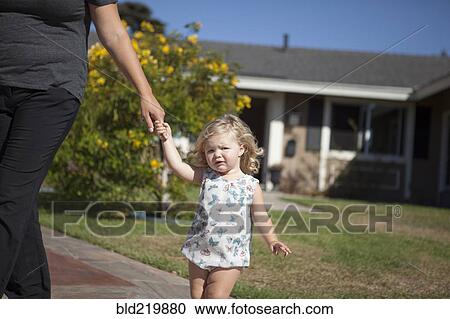 Stock Image - Mother and daughter walking on sidewalk. Fotosearch