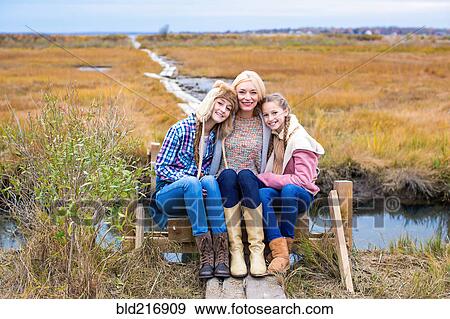 Mother and daughters hugging on walkway in rural field View Large Photo Image Stock Photo - Mother and daughters hugging on walkway in rural field. Fotosearch