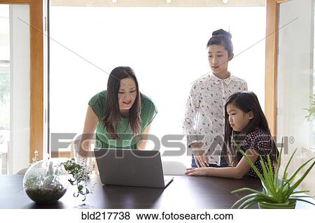 Mother and daughters using laptop in dining room View Large Photo Image Stock Photo - Mother and daughters using laptop in dining room. Fotosearch