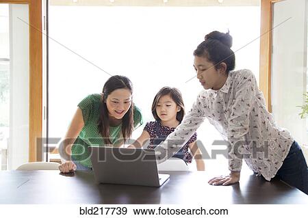 Mother and daughters using laptop in dining room View Large Photo Image Stock Photo - Mother and daughters using laptop in dining room. Fotosearch